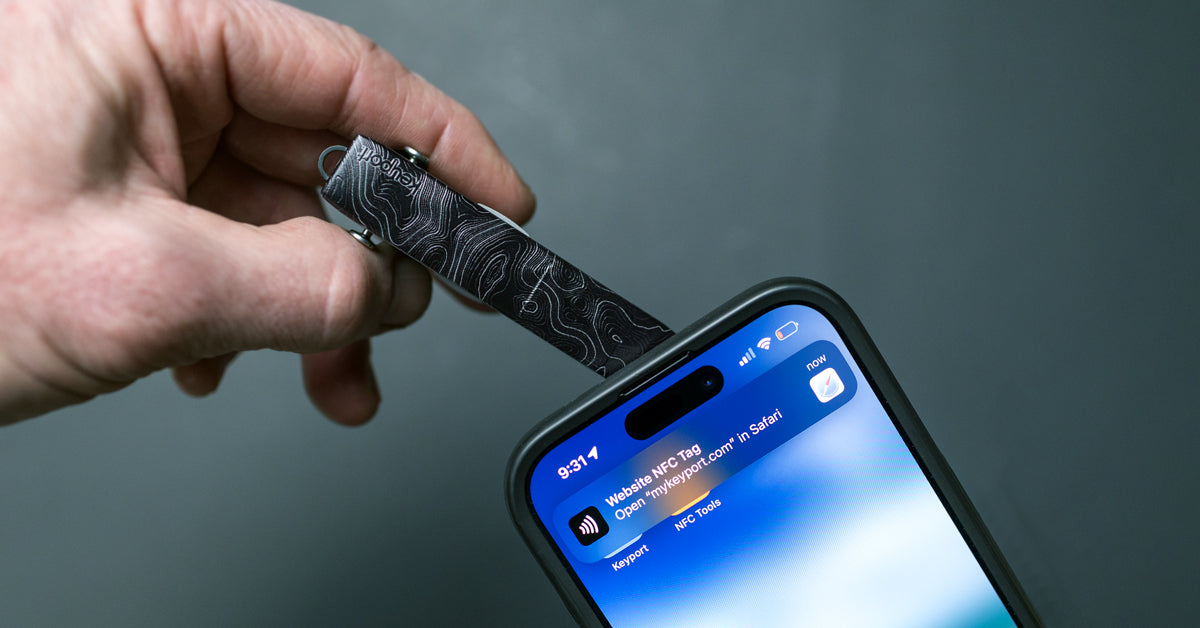 Hand tapping a topographic Keyport NFC Tag Faceplate on a key organizer to an iPhone to open a link