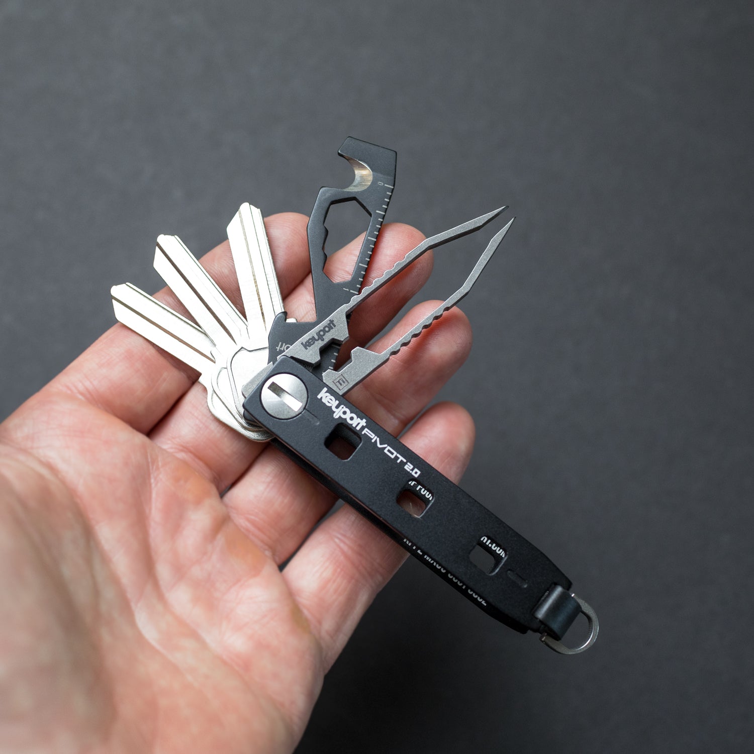 Black Keyport Pivot 2.0 securely holding 3 key blanks, black MOCA 10-in-1 multi-tool, and titanium tweezer Insert
