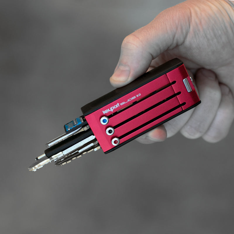 Red 6-port Keyport Slide 3.0 key holder with keys and tools deployed in hand