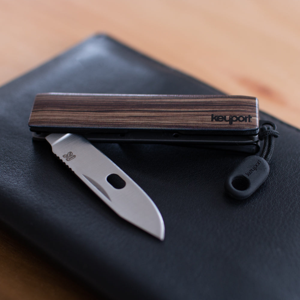 NEBA Knife Module with zebra wood faceplate on top of a leather wallet